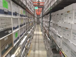 View looking down an aisle of DeVries records center with many boxes stacked on warehouse shelves