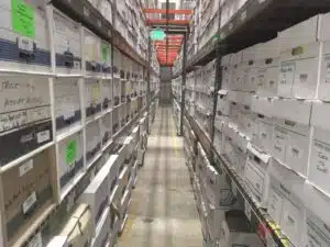 View looking down an aisle of DeVries records center with many boxes stacked on warehouse shelves