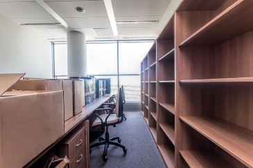 Empty shelves, desks, chairs and cardboard boxes stacked during the office moving process