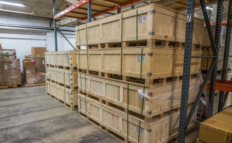 Large wood crates are neatly stacked in a tidy warehouse.