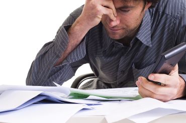 Man looking stressed with lots of messy paperwork