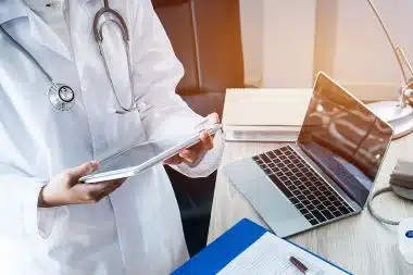 Doctor wearing stethoscope is searching information on tablet in medical facility