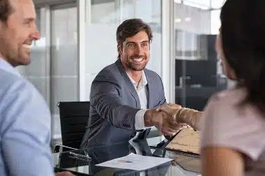 A smiling financial services professional is shaking hands with a client