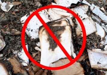 Partially burned documents lay in a pile of ashes and a NO symbol is overlaying the image.