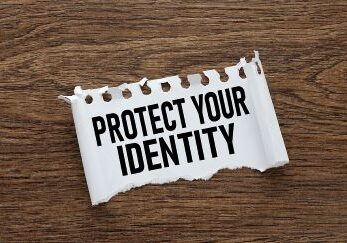 The words "Protect Your Identity" are shown in black letters on a white piece of torn paper that is laying on a table surface.