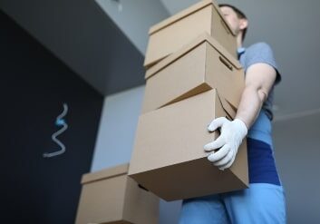 Loader man carries cardboard boxes in office