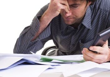 Man looking stressed with lots of messy paperwork